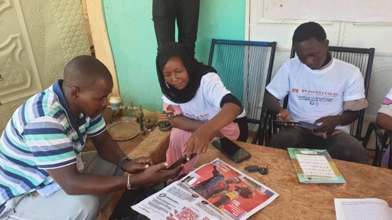 A woman indicates to a man something on a smartphone.